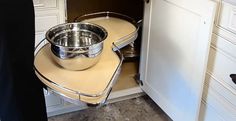 a metal bowl sitting on top of an open cabinet