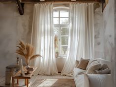 a living room filled with furniture and a large window covered in white drapes