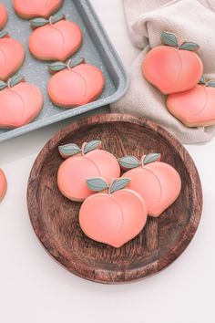 there are some cookies shaped like peaches on a plate next to the cookie sheet