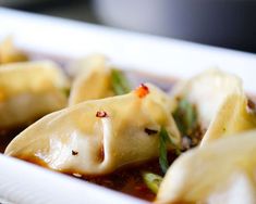 some dumplings are sitting in a white dish