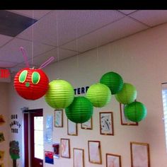 some green and red paper lanterns hanging from the ceiling in a room with pictures on the wall