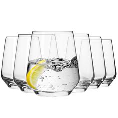 several glasses filled with water and lemon wedged into each other on a white background