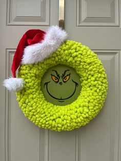 a grin face wreath hanging on the front door with santa's helper hat