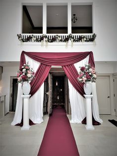 a red carpeted hallway with white columns and flowers