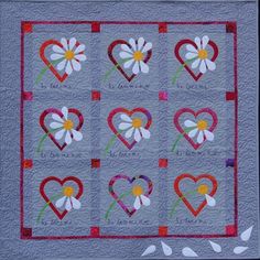 a quilted wall hanging with hearts and daisies in the shape of heart's