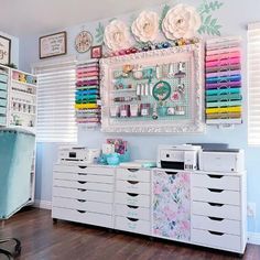 a sewing room with lots of crafting supplies on the wall and drawers in front of it