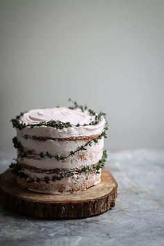 a cake with white frosting and sprigs on top sitting on a wooden board