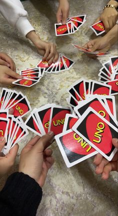 several people holding up playing cards with the word uno written on them in red and yellow