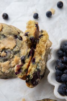 two blueberry muffins next to a bowl of berries