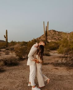 a couple kissing in the desert surrounded by cacti