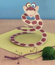 a paper snake sitting on top of a green piece of paper