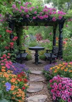 a garden filled with lots of flowers next to a stone path covered in pink and orange flowers