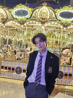 a man standing in front of a merry go round carousel at night with his hands in his pockets