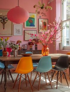 a dining room with pink walls and colorful chairs