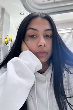 a woman with long black hair wearing a white hoodie and looking at the camera