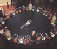 there are many glasses and bottles on the table with drinks in them, all arranged in a circle