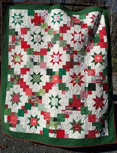 a green and red quilt hanging from a tree