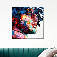 a colorful painting of a man's face on a white wall above a green couch