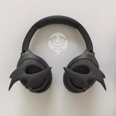 two black headphones sitting next to each other on top of a white surface with a logo in the middle