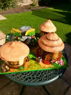 a table that has some grass huts on top of it in the middle of a yard