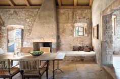 an old stone house with a fireplace and dining table