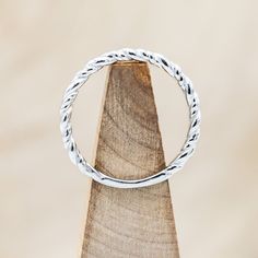 a silver ring sitting on top of a piece of wood