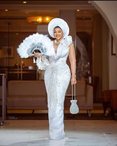 a woman in a white dress holding a fan