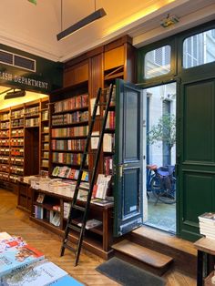 an open book store with ladders and bookshelves in front of the door