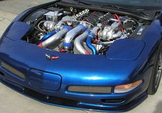 a blue sports car with its hood open and the engine in it's trunk