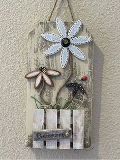 a wooden sign hanging on the side of a wall with flowers and words painted on it