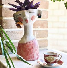 a vase with flowers in it sitting next to a cup and saucer