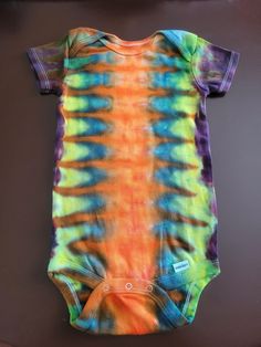 a tie - dyed bodysuit is hanging on the wall