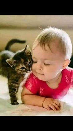 a small child laying on top of a bed next to a cat