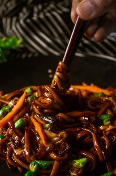 someone is stirring some food in a wok with chopsticks to stir it