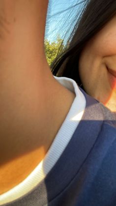 a close up of a person's face with the sun shining on her and trees in the background