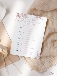 a white wedding program sitting on top of a table next to a lamp and blanket