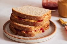 three sandwiches stacked on top of each other next to a jar of jam and a pair of scissors