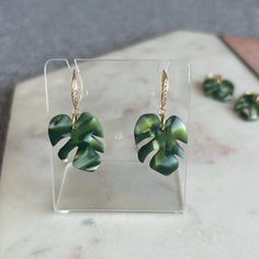 🍃 Treat yourself and your loved ones with these gorgeous monstera deliciosa leaf earrings! Perfect earrings for plant lover who value handmade creations. Forest green color with  variegated effect, very beautiful and unique tropical leaf earrings.  With gold plated hooks that add shine and elegance to the pieces, very lightweight for comfortable wear. 🍃 Ear wire material-gold plated. Drop Length is approx 3.5 cm 🍃 Due to handmade nature of the pieces, slight color variations may occur. Please Monstera Leaf Earrings, Variegated Monstera, White Jewelry Box, Forest Green Color, Monstera Deliciosa, Plant Lover Gift, Earrings Polymer Clay, Tropical Leaf, Branded Gifts