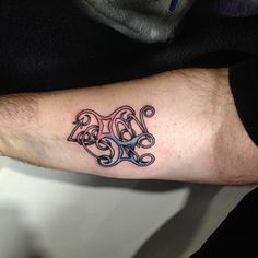 a man's arm with a tattoo on it that has the letter b in different colors