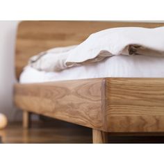 a wooden bed with white sheets and pillows