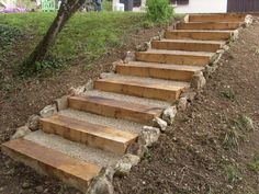 some steps made out of wood are in the dirt near a tree and grass area