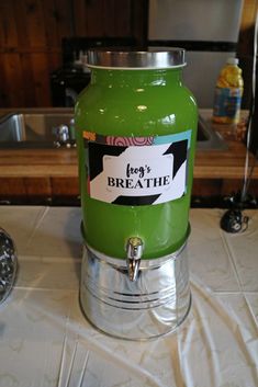 a green beverage dispenser sitting on top of a white cloth covered table