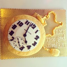 a cake shaped like a clock on top of a gold platter with the words, let the good times roll