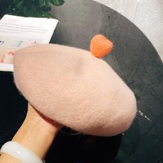 a woman's hand holding a pink hat with an orange felt heart on it