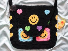 a black crocheted bag with smiley faces on it