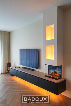 a living room with a television and fireplace in the center, surrounded by wood flooring