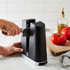 a person using a knife to cut tomatoes on a cutting board