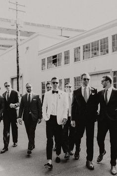 black and white photograph of men in suits walking down the street with one man wearing sunglasses