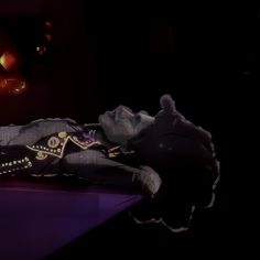 a woman laying on top of a purple table next to a black cat and red light