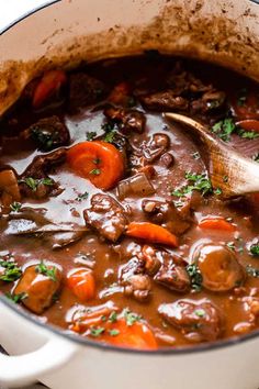 beef stew with carrots and mushrooms in a white pot